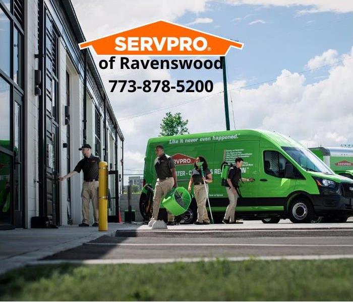 Green SERVPRO truck and employees outside of a building.